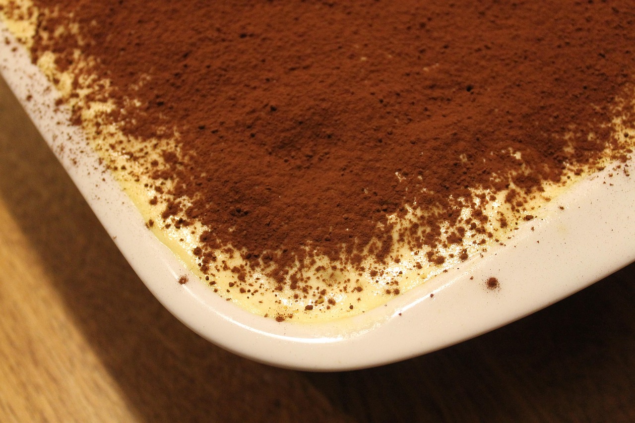 Tazza di tiramisù decorato con cacao e cucchiaino, simbolo della ricetta perfetta.